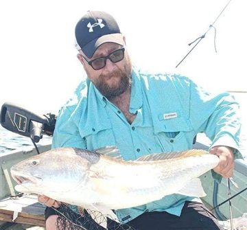 Eddie Smith holding a redfish on a boat